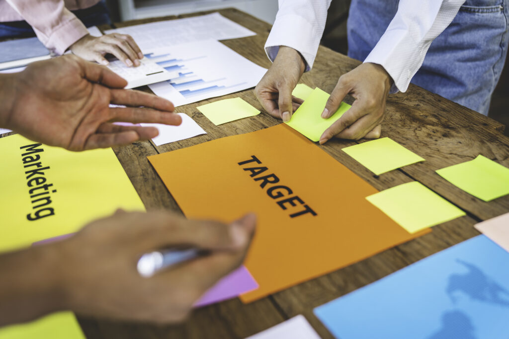 A team of marketing professionals strategizing using sticky notes and other materials.