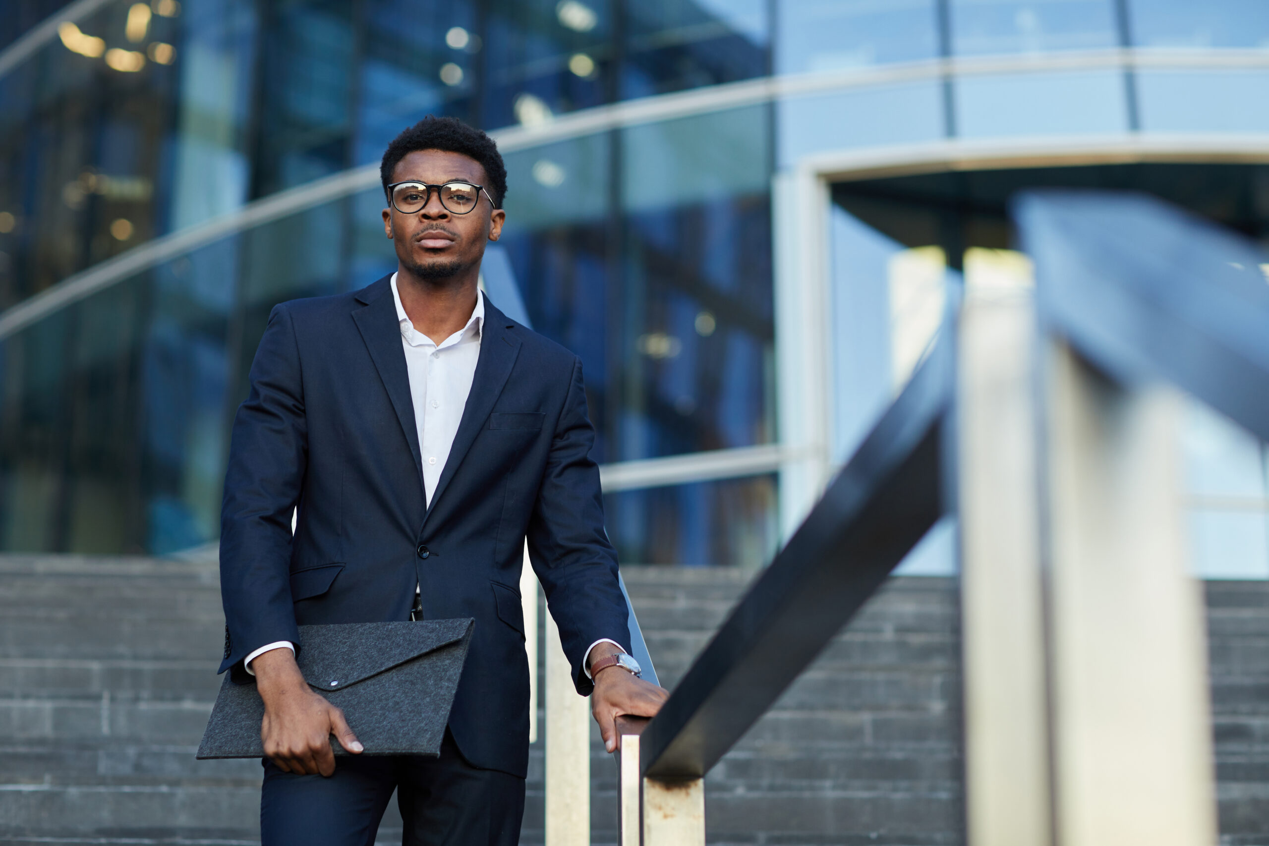 A young, confident business professional standing confidently outside an office building.