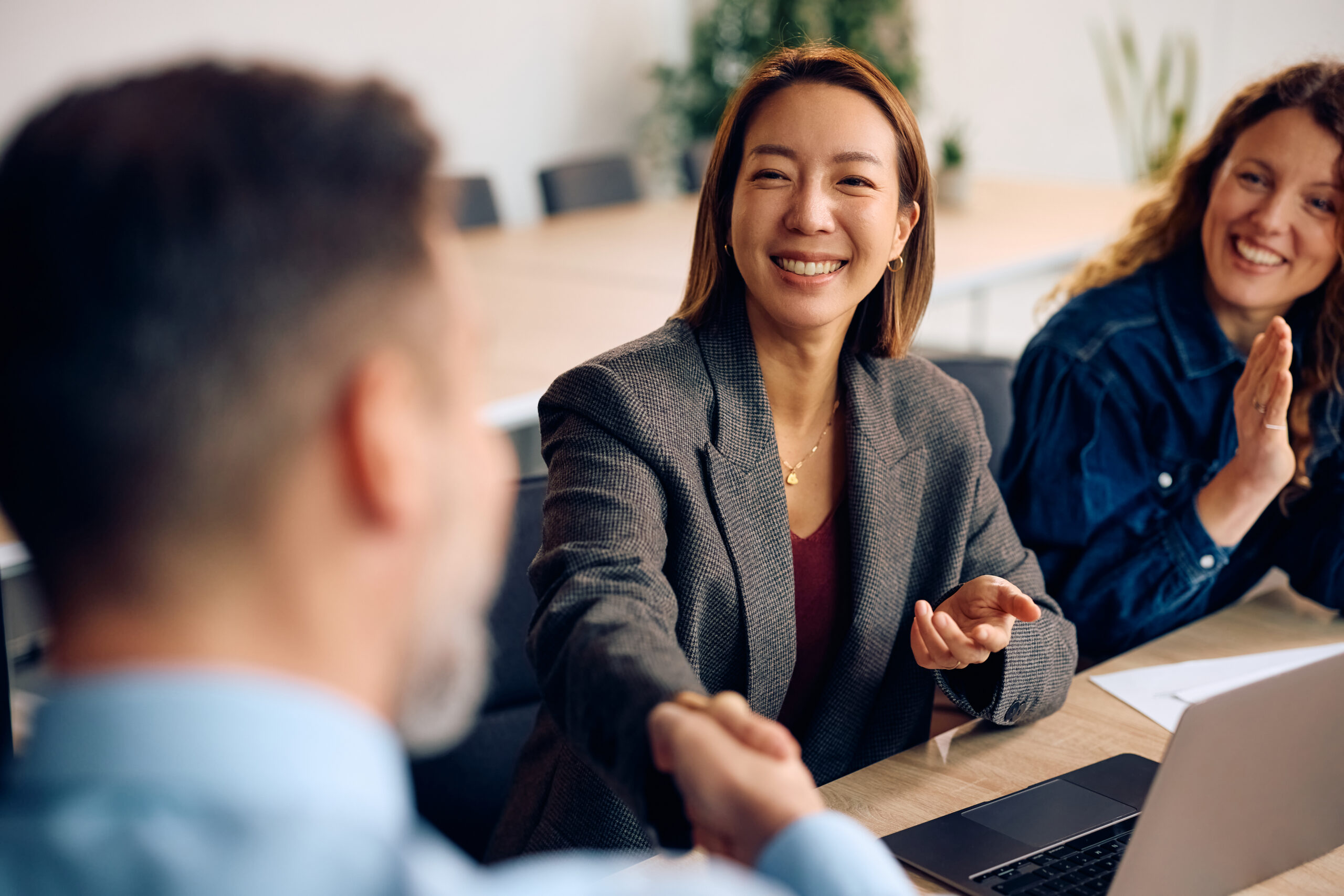 A cheerful business professional shaking hands with another individual in a boardroom setting